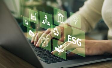 Hands typing on a laptop keyboard with virtual icons representing ESG (Environmental, Social, and Governance) concepts displayed above, including symbols for sustainability, recycling, and institutions.